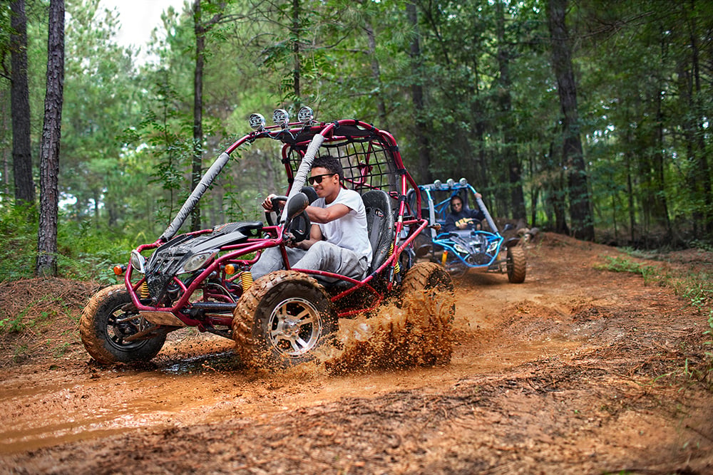 Two men race ATVs on a muddy track in Fayetteville, North Carolina.