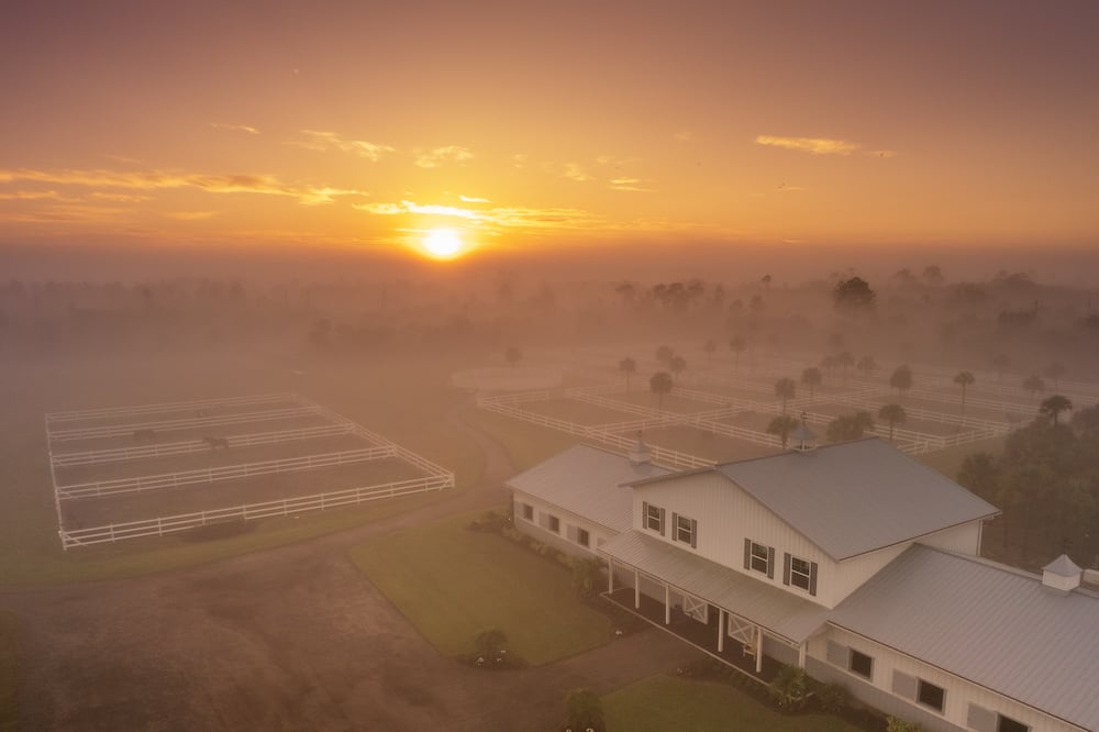 Drone shot overview of farm and horse pens in heavy morning haze,  by Fort Myers, FL-based lifestyle photographer Brian Tietz.