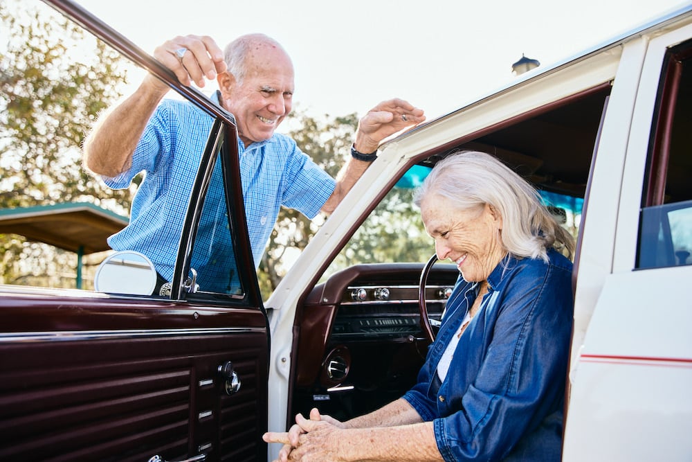 Image of couple smiling naturally with wife seated in driver's and husband standing with hands on the roof and door, by Altamonte Springs, Florida-based portrait photographer Brian Carlson. 