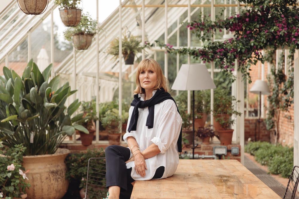 Portrait of Chef Skye Gyngell sitting on greenhouse table, surrounded by plants, at Heckfield Place, by London-based portrait photographer Dunja Opalko.