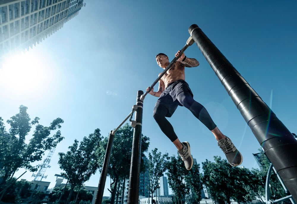 Athlete doing pullups outside at park for Dymatize.