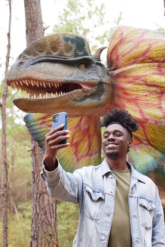 Man captures selfie with life-size dinosaur replica in a Fayetteville, North Carolina adventure park. Taken by Durham-based lifestyle photographer Natalia Weedy.