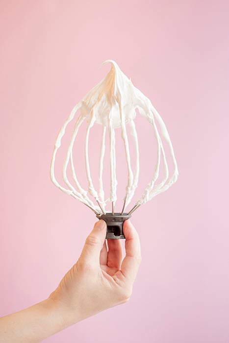 A whisk with frosting photographed by Maria Clark. 