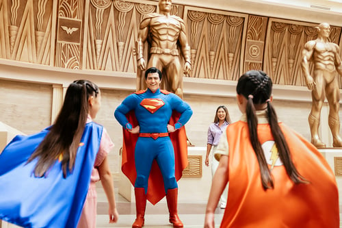 Two children in capes meet a costumed Superman in Abu Dhabi theme park, for their tourism campaign shot by Tom Parker.