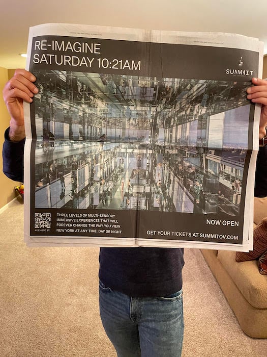 Craig holding up a double page spread of an ad for Summit in the NY times