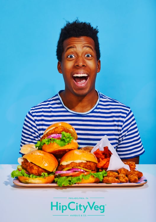 Photo by Stevie Chris of a happy man in front of a packed tray of vegetarian fast food.