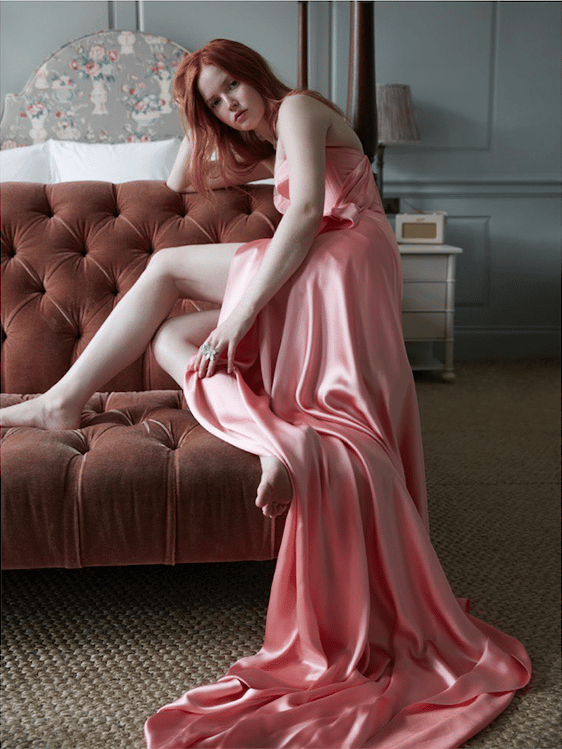 Photo by Alan Gelati of a model resting on a sofa in a lush pink gown.
