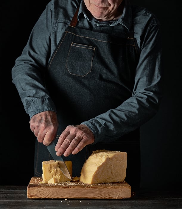 Cheesemonger cuts a block of cheese. Photographed by John Valls for Tillamook Creamery.
