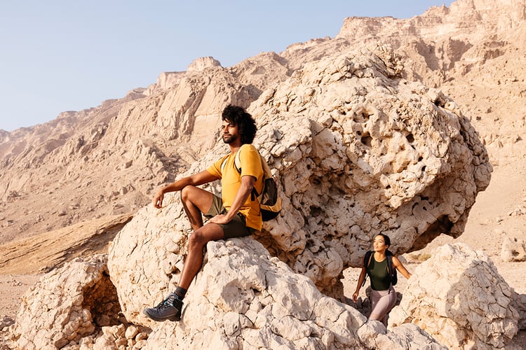 A man and woman hike in the desert in Abu Dhabi, UAE, shot by photographer Tom Parker.