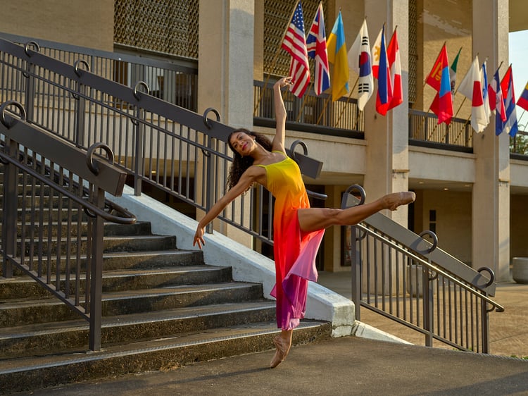 Photo of ballet dancer on pointe in front of staircase with international display of flags, by Tuscaloosa, Alabama-based music/performing arts photographer Michael J. Moore.