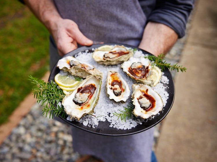 Photo by Darren Hendrix of a man holding an iced tray of oysters.
