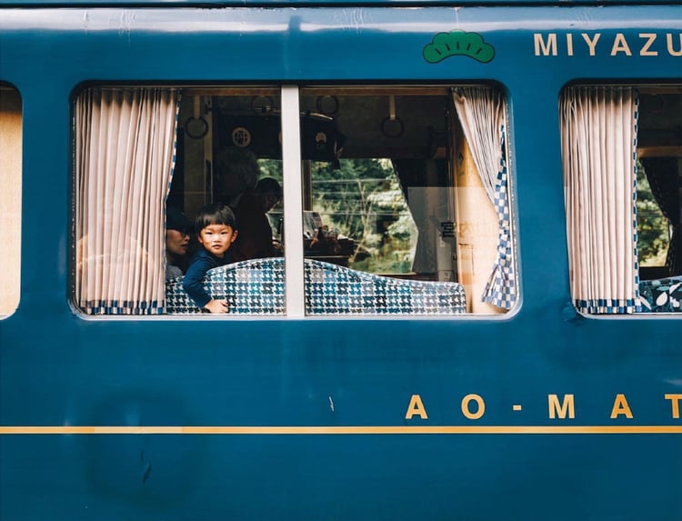 Photo by Lauryn Ishak of a boy and his family looking out the window of a blue train car.