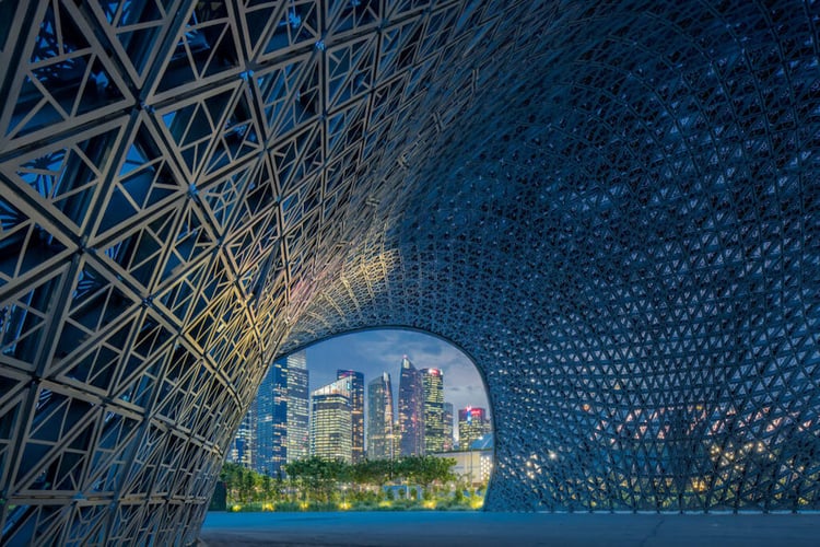 Photo by Todd Beltz of a curved metal waterway tunnel looking out to a skyline of many skyscrapers.
