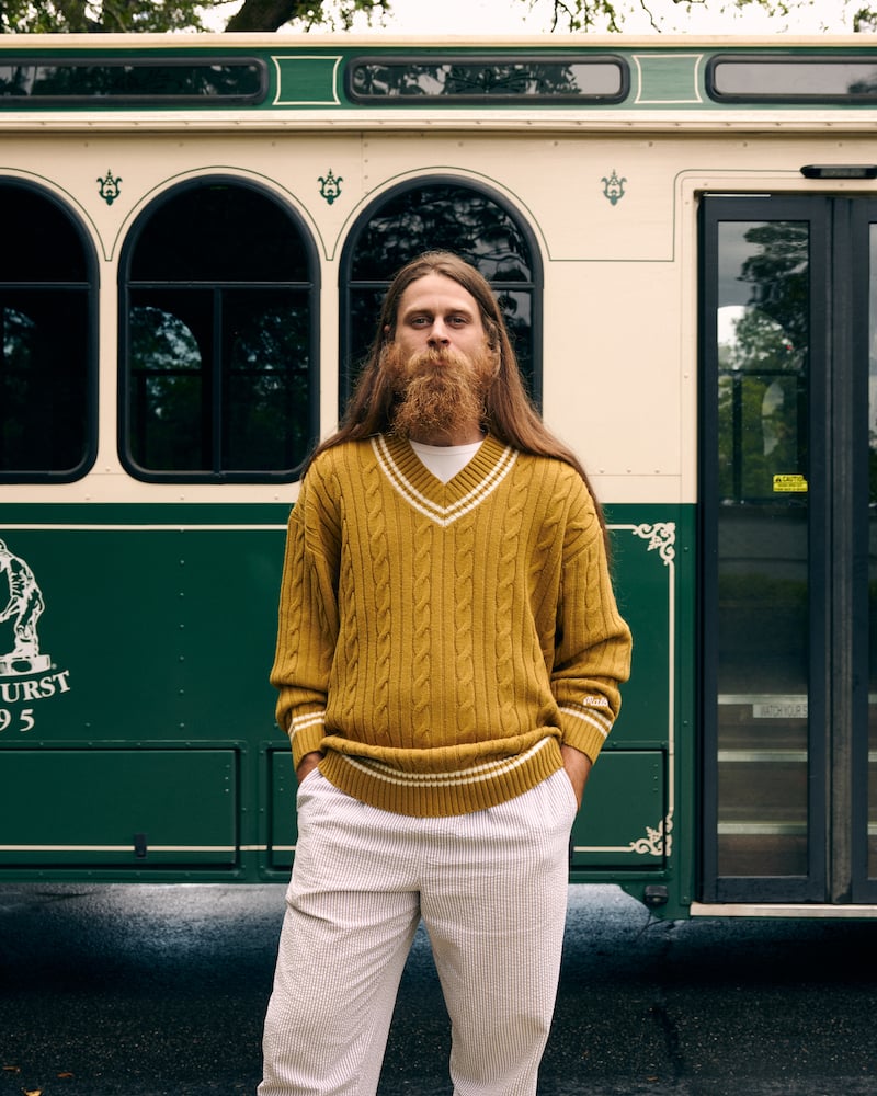 Photo of long-haired bearded figure standing in mustard sweater before green bus, by Charlotte, North Carolina-based fashion photographer Jackson Ray Petty.