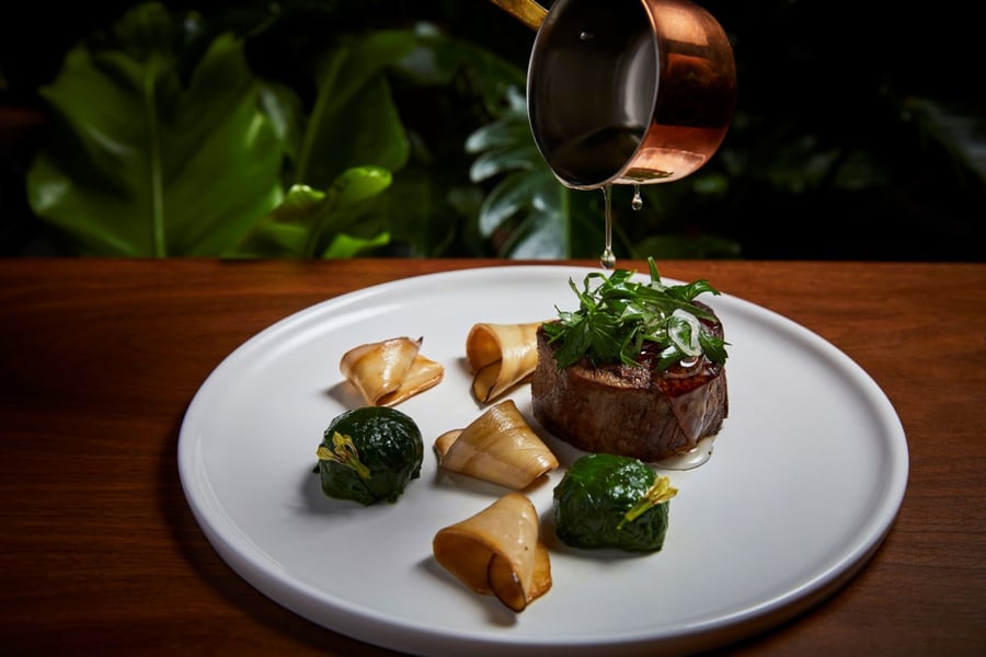 Andrea D'Agosto's photo of a brass cup pouring sauce over a plated meal for Edition Hotel 