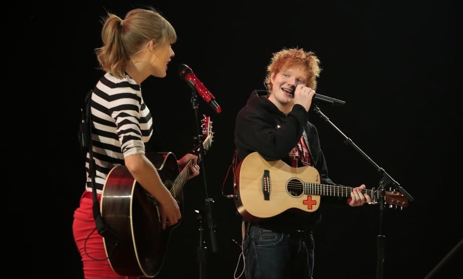 A photo of Ed Sheeran as a teen onstage with a guitar, singing with Taylor Swift