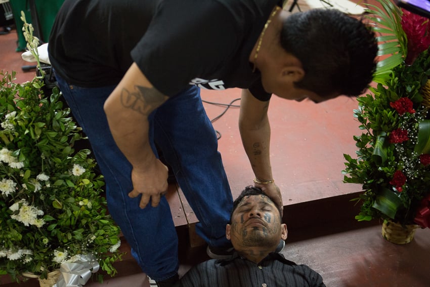 Photo of a pastor praying above an ex-gang member published on NPR taken as part of an IWMF Adelante reporting fellowship by Alicia Vera.