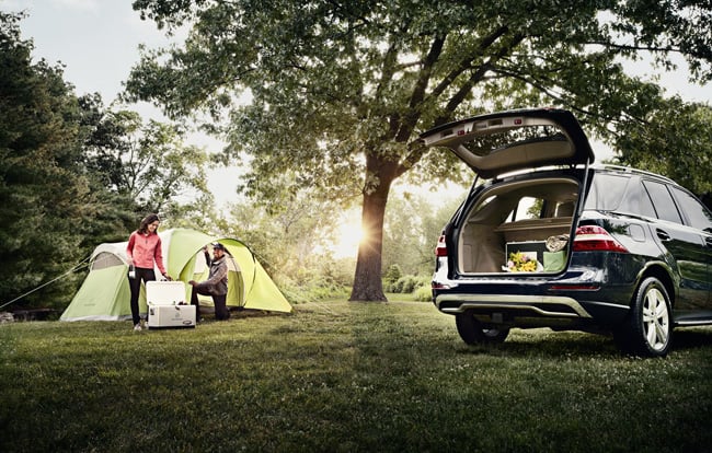 A couple setting up a tent near their car, for a commercial photography shoot 