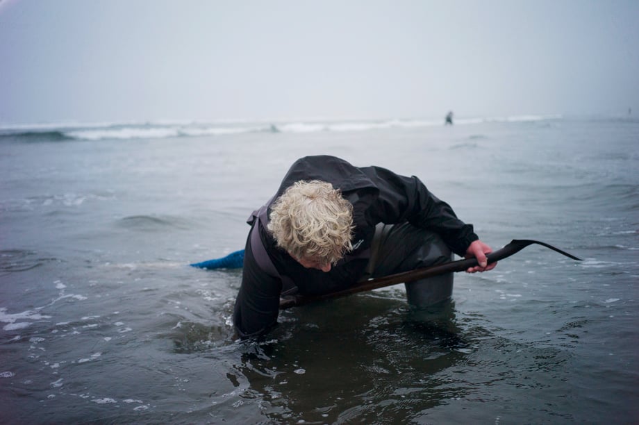 Richard Darbonne photographs Ron Neva as he reaches down into the water in hopes of finding a razor clam for 1859 Magazine