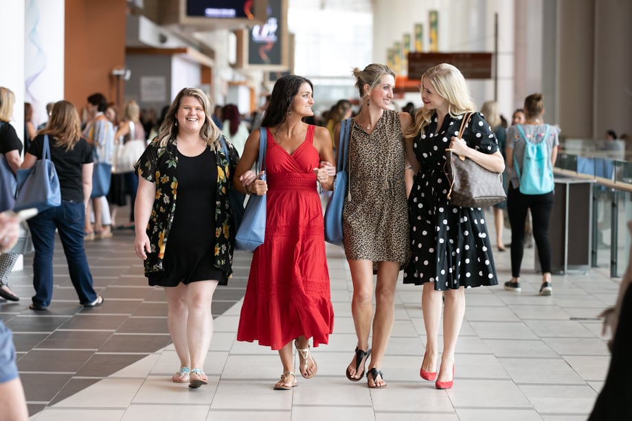 Four women walk towards Margo Moritz while engaged in conversation at a convention