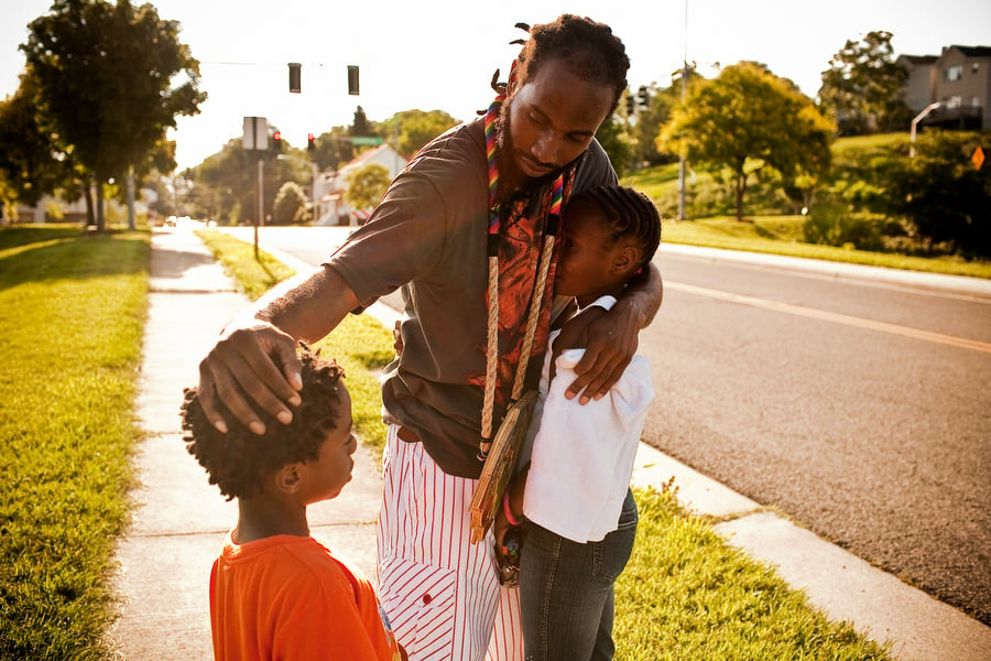 Intimate portrait of a man hugging his kids in a suburban neighborhood captured by Jared Soares.
