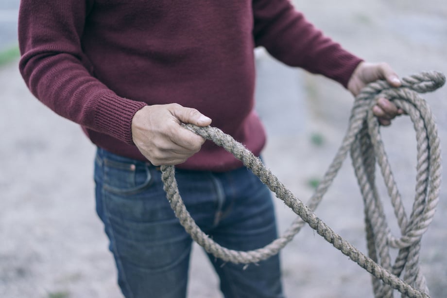 Mackenzie Duncan shows a fisherman arranging rope in a maroon recycled wool sweater and jeans