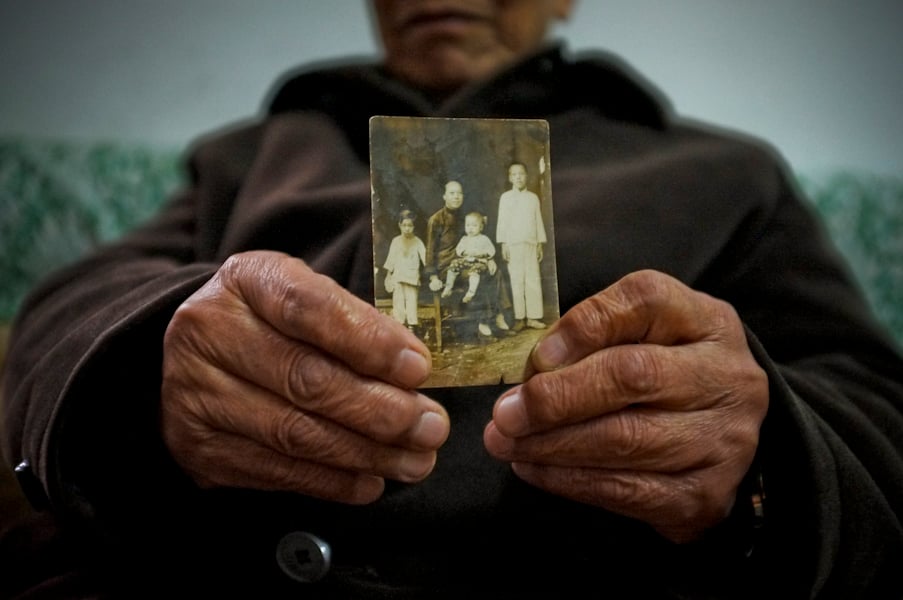 Amanda Mustard photograph of a survivor holding a family photo