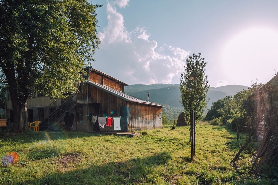 A Georgian farmhouse is set against a mountain range on a sunny day in this  landscape photo by Dimitri Mais
