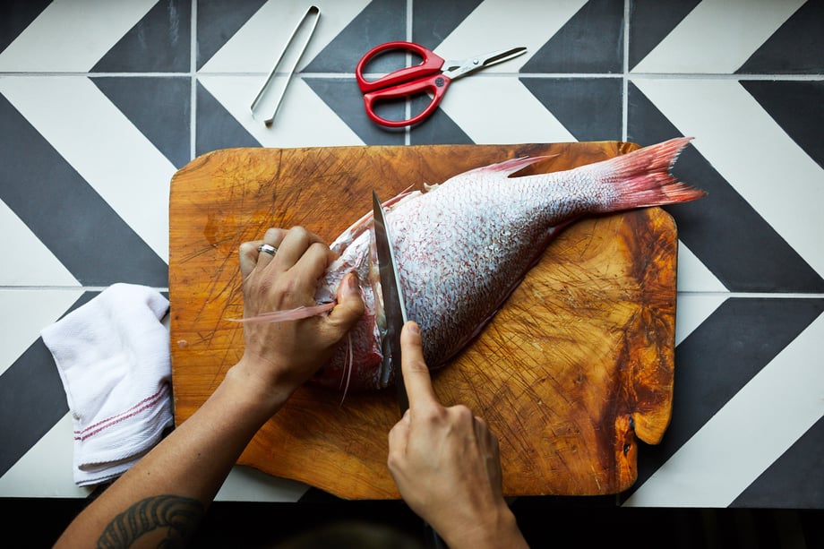 Jody Horton shows from above a fish being filleted on a wooden cutting board