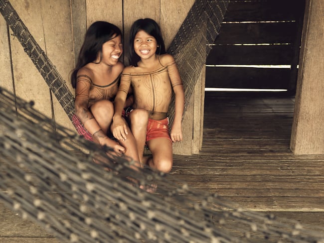 Two Embera friends giggle on a hammock shot by London-based photojournalist Piers Calvert