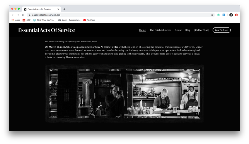 Screenshot of Andrew Dolph's Essential Acts of Services website featuring the photographer shooting himself in reflection next to two kitchen workers.