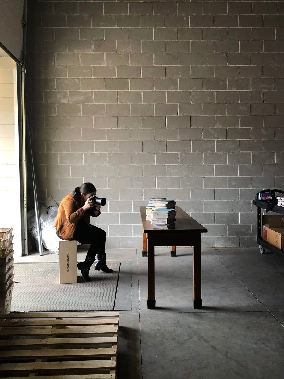 This behind the scenes shot shows Kat Schleicher photographing stacks of books in the loading dock