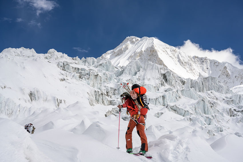 Blake Gordon's image for The North Face shows a climber in full gear with icy summit against a blue sky in the background.