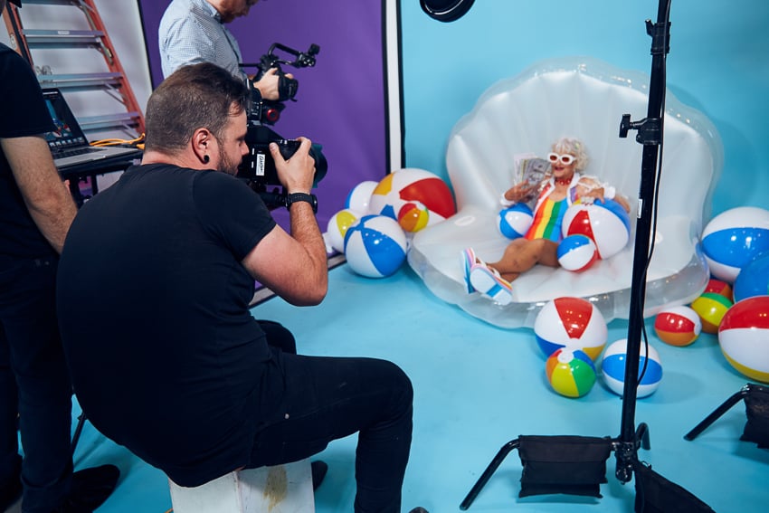 Clay Cook photographing Instagram star Baddie Winkle holding pretend, oversized hundred dollar bills in a giant clamshell for Stash Investing.