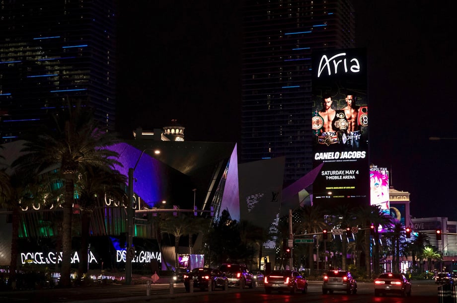 A digital billboard on the side of a Las Vegas hotel shows the AK Collective poster featuring Canelo vs Jacobs