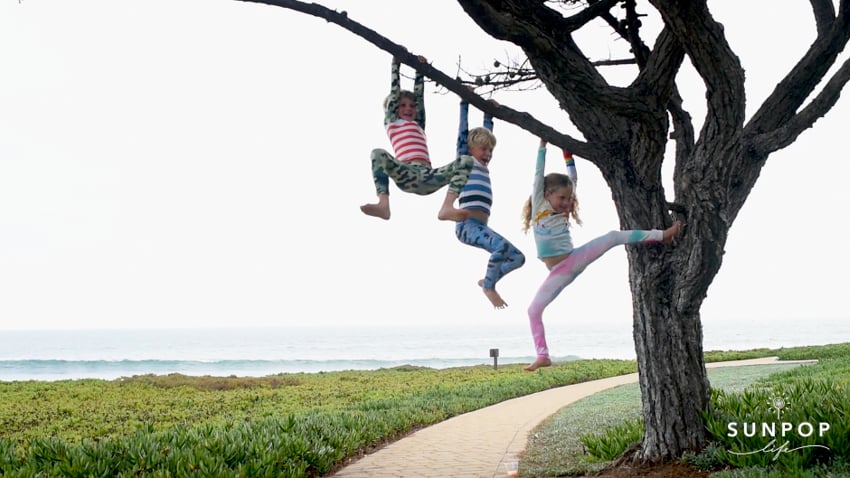 Photo of kids wearing SunPopLife swimsuits hanging from a tree shot by photographer Caroline Woodham.