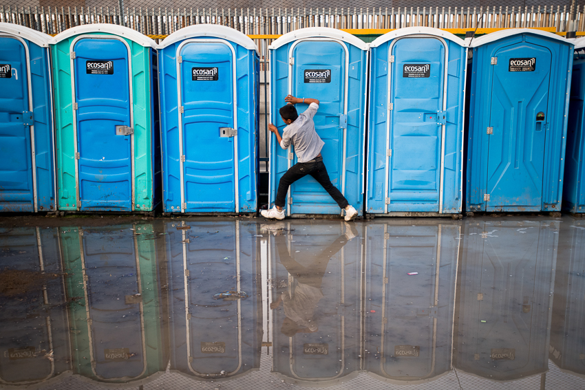Sean Rayford Image of Central American Migrants as a young man tries to move a port-o-john