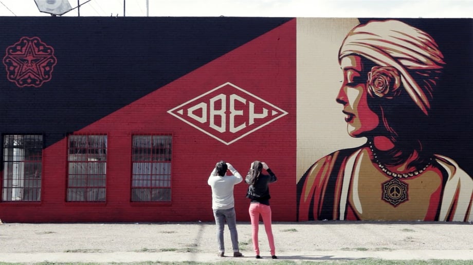 Two people taking photos by a Shepard Fairey mural shot by  Dallas-based portrait photographer Justin Clemons