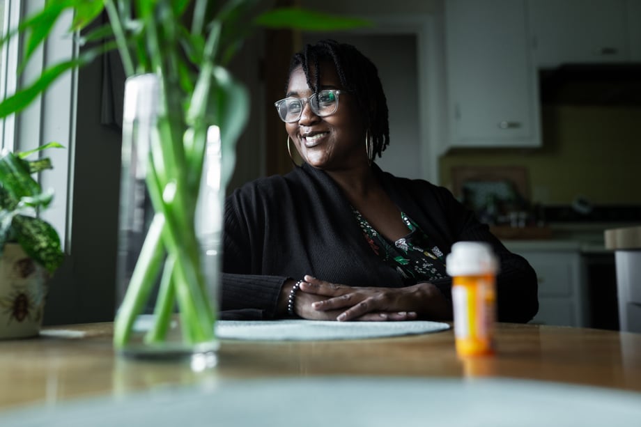 Craig Okraska photographs smiling woman at her kitchen table for the LOR Foundation