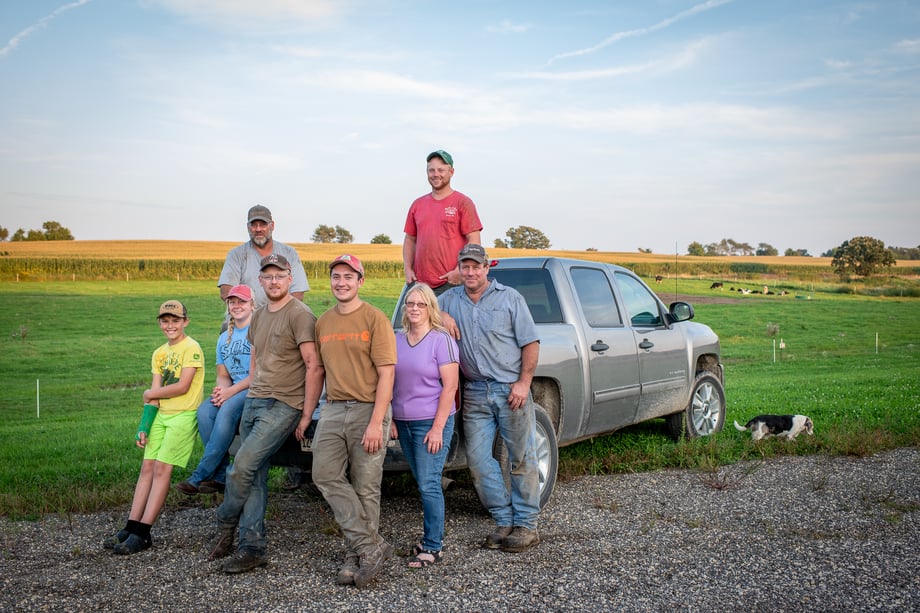 Chad Holder has a farming family posed on the bed of a pickup truck at the edge of a field