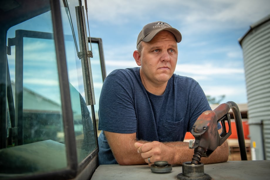 Chad Holder's portrait of Mark Fellwock leaning on the back of a truck as he fills it with gas