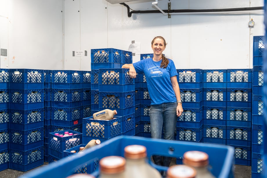 Chad Holder's photo of Melissa Reed, standing among stacked blue crates of milk at her dairy processing facility