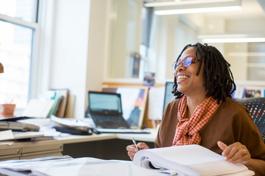 An image of a woman smiling at her desk from the Corporate section of Dan Bigelow's website.