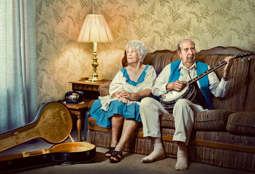 Elderly couple in living room wearing costumes and holding a banjo.