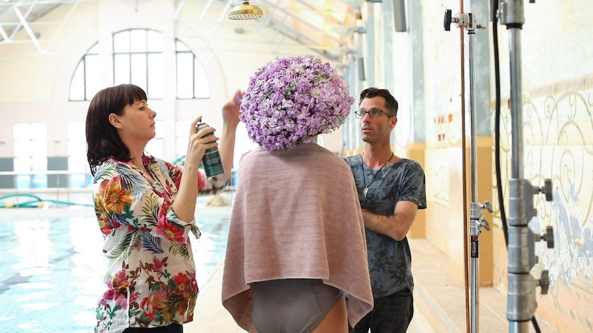 Stylist and photographer work together to keep flowers arranged.
