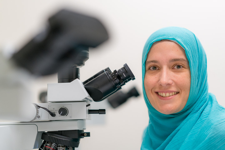A Janssen scientist smiles in front of her microscope. 