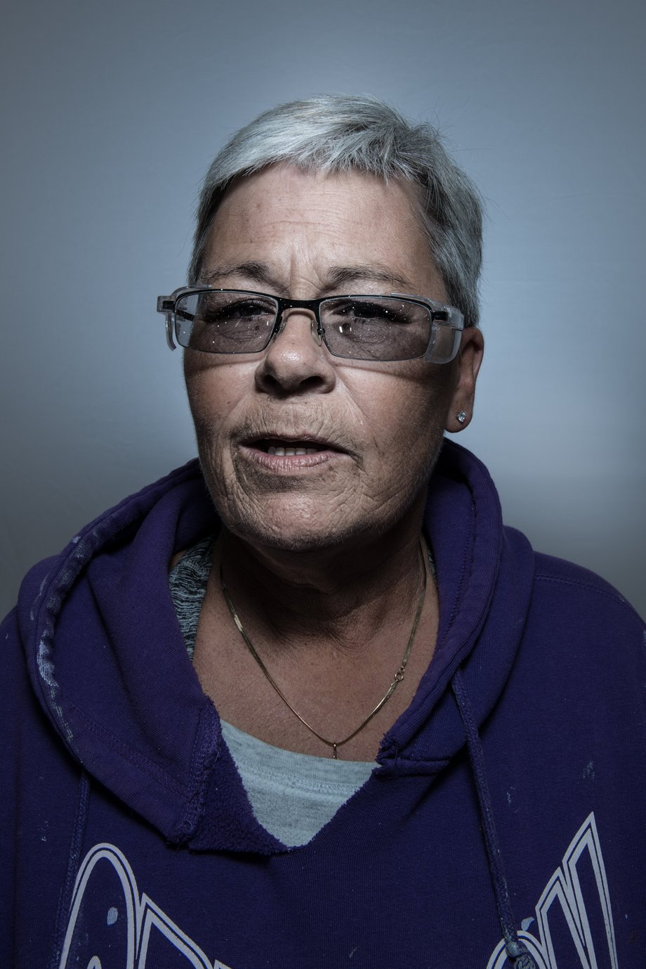 Heather Perry's portrait of Kim, and older woman with short, grey hair in a purple hoodie sweatshirt and glasses