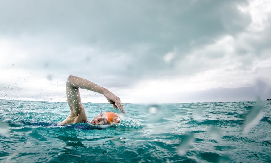 Heather Perry's "underwater" image featuring a swimmer in a storm in what looks like an ocean with crystal clear blue waters for SwimVacation