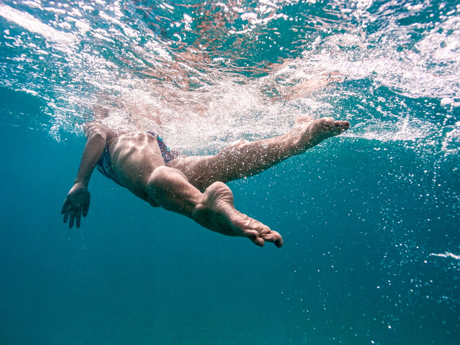 Heather Perry's underwater image from below and behind a swimmer with the light bouncing through the water and bubbles