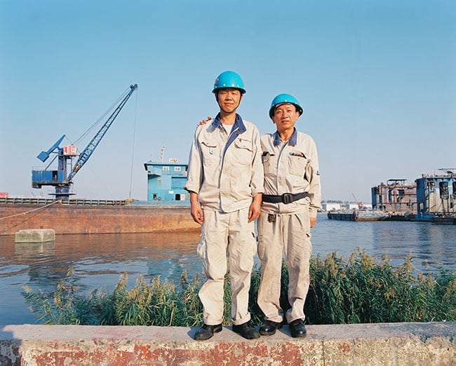 Two employees in hard hats pose next to the Huangpu river, photo by Jonathan Browning 